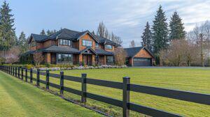 Black split rail fence in front of a nice home