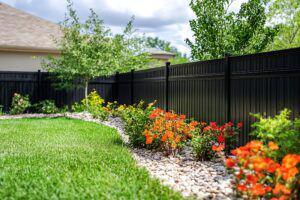 Black backyard fence with landscaping
