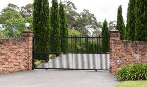 Black metal driveway entrance gates in brick fence