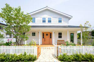 Wood picket fence in front of a white farmhouse style home
