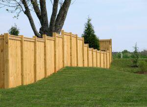 Stepped wood cap and trim fence on a uneven property