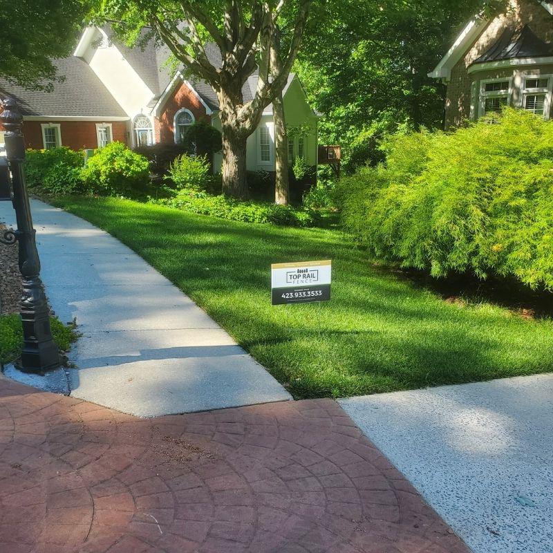 Top Rail Fence yard sign staked in the ground in front of a home