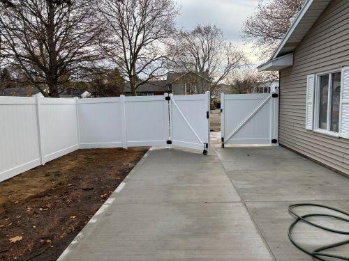 6 foot high white vinyl privacy fence with gate on concrete