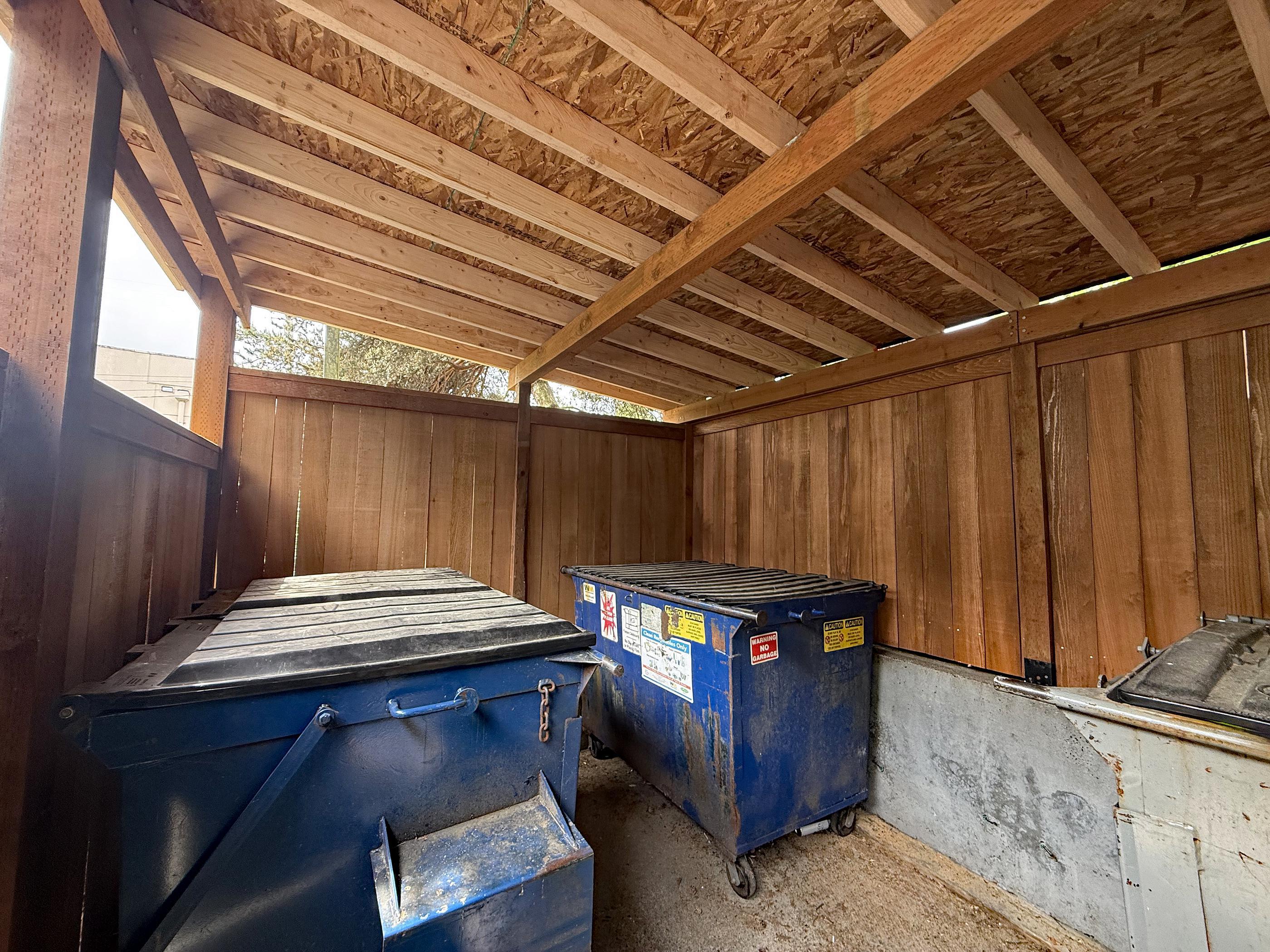 wood dumpster enclosure installed by top rail fence