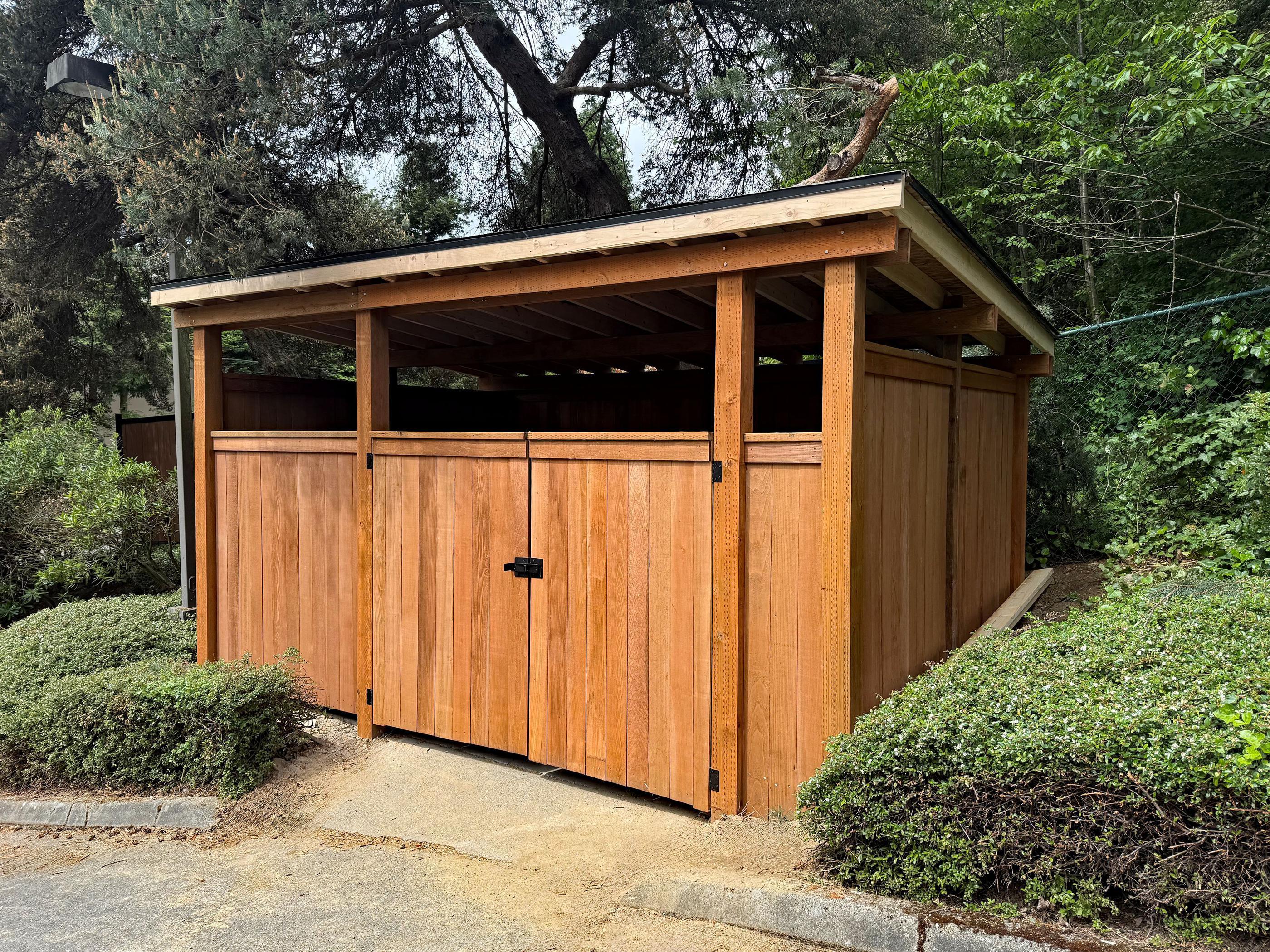 wood dumpster enclosure installed by top rail fence