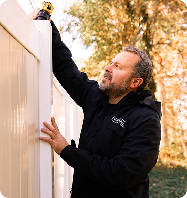 Top Rail team member installing a fence panel with professional tools on a job site