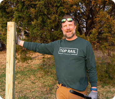 Top Rail employee standing beside a wooden pole outdoors