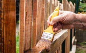 Wood fence being stained by hand