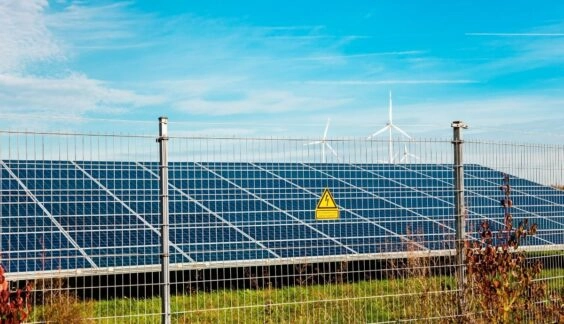 Electic fence in front of solar panel and windmill farm