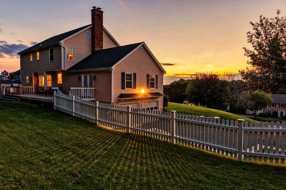 A suburban home in the evening with a picket fence
