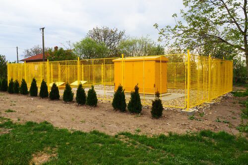 Yellow commercial fencing around a utility building.