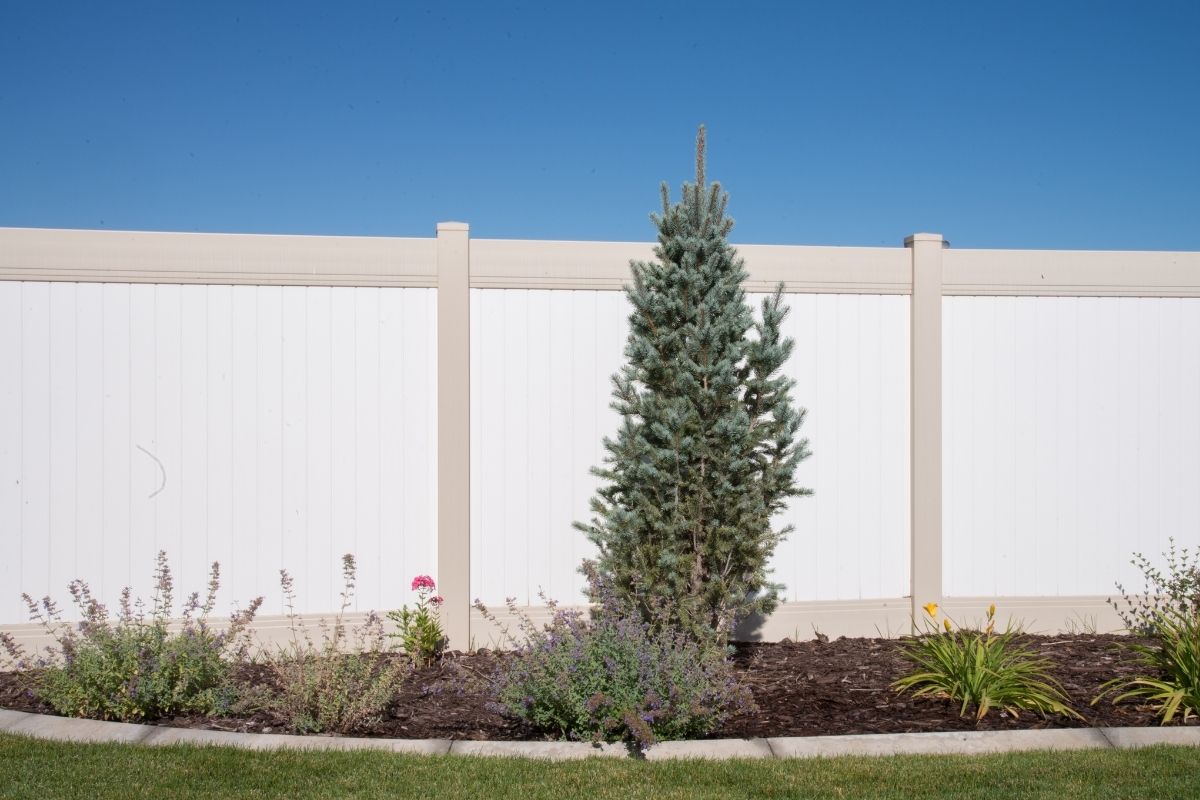 white vinyl fence with tan trim and landscaping