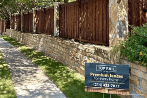 A new fence installed by Top Rail Fence with the companies yard sign out front of the fence