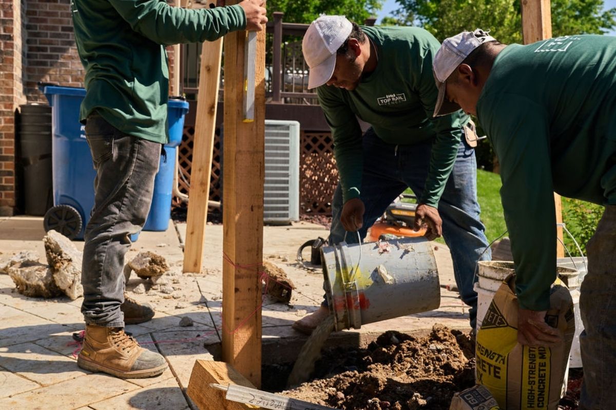 image of Top Rail Fence installers pouring wet concrete